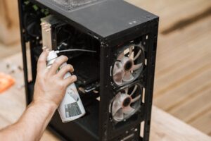 Home A person using compressed air to clean a computer case, focusing on dust removal.